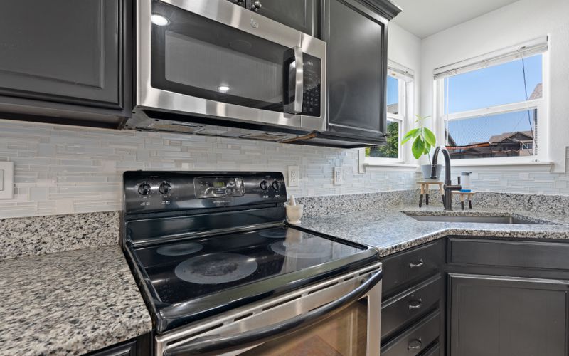 Stylish modern kitchen with stainless steel microwave, stove, and granite countertops — microwave buying guide Uganda