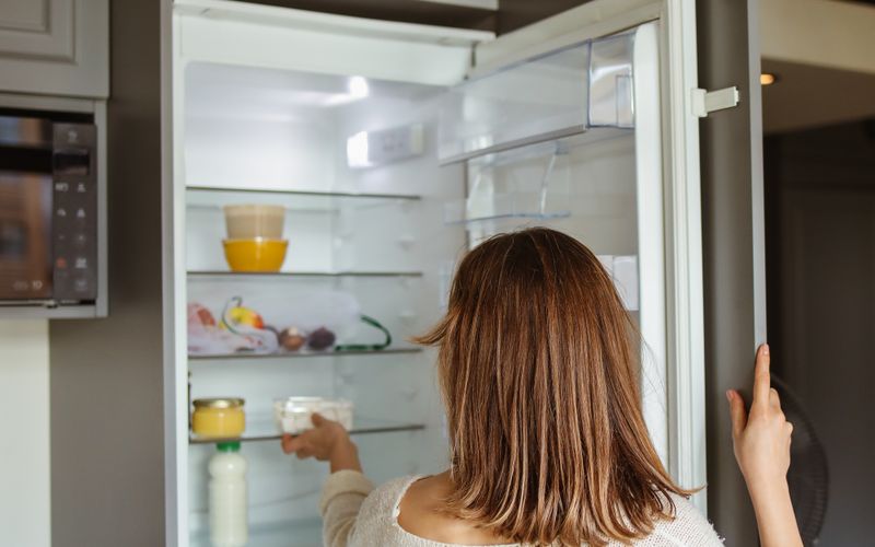 Woman reaching into a modern refrigerator in a contemporary kitchen