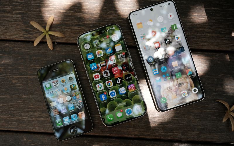 Collection of modern smartphones showing different app icons on a wooden surface in natural light