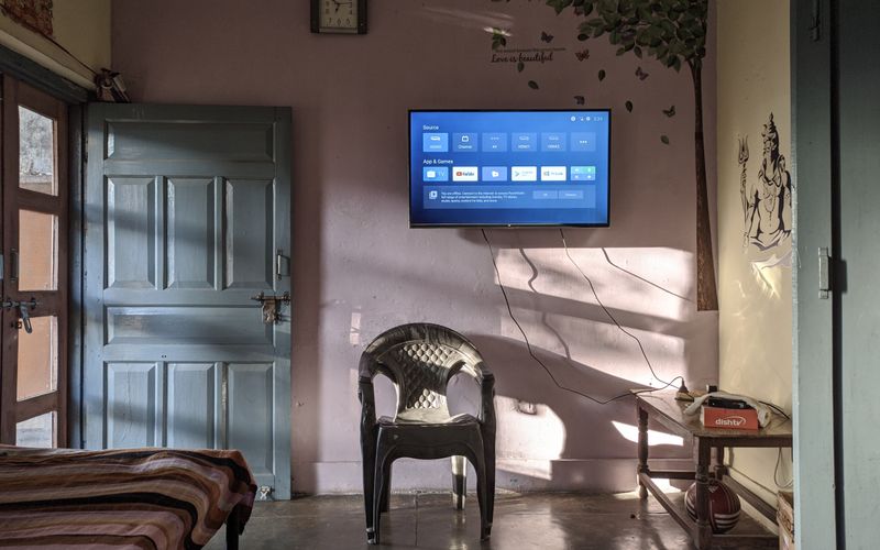 Sunlit living room with wall-mounted TV and wooden furniture — budget TVs under UGX 1 million in Uganda