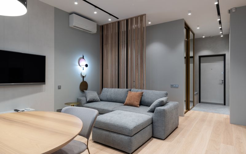 Modern living room with comfortable gray sofa and wall-mounted TV — Samsung vs LG TV comparison