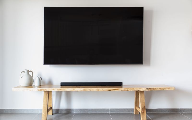 Stylish minimalist living room with wall-mounted flat screen TV and wooden console — TV size guide for Ugandan homes