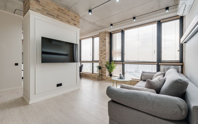 Modern living room with wall-mounted TV, gray sofa, and stylish decor — best TVs in Uganda 2026