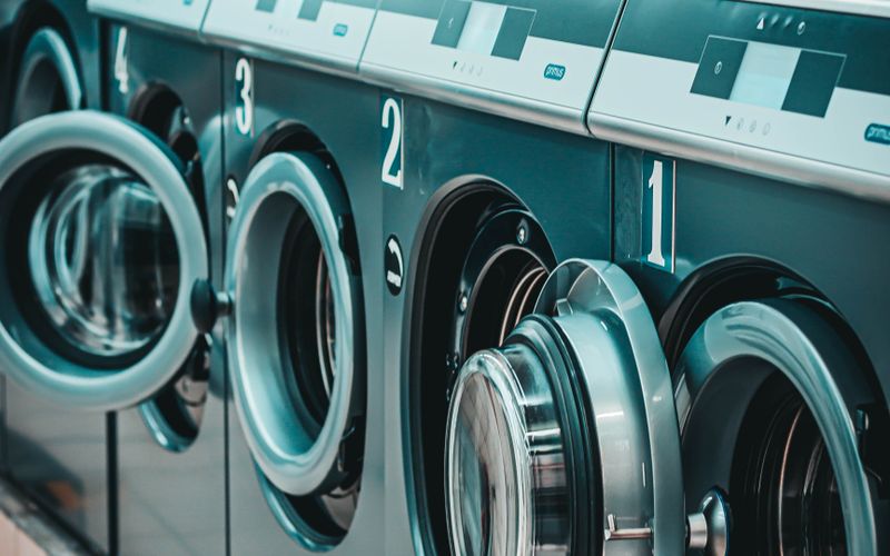Row of contemporary numbered washing machines on tiled floor in bright laundry room