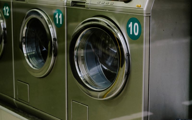 Clean modern laundromat with stainless steel washing machines lined up