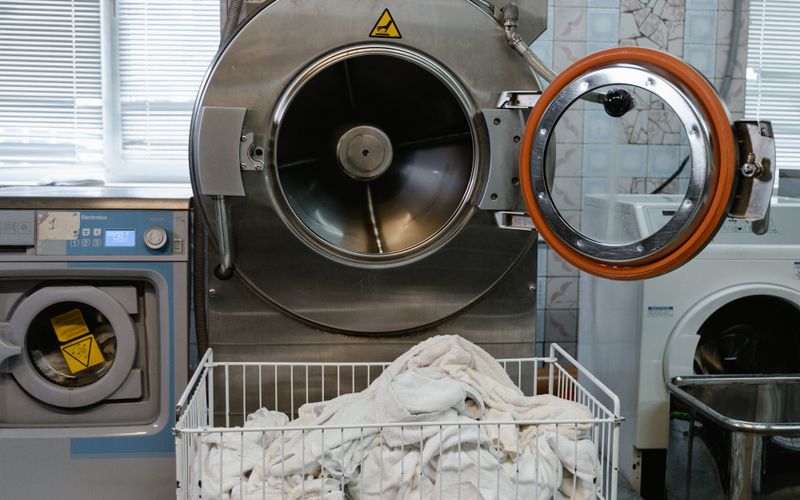 Large industrial washing machine with a cart full of linens in a laundry facility